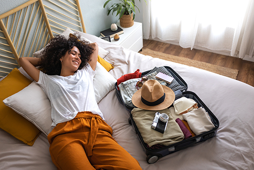 Young professional with packed luggage on bed